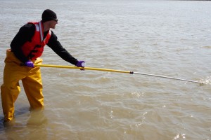 Researcher Matt Alkire uses a telescoping pole to collect water from the river. (Photo credit: Rob Macdonald)