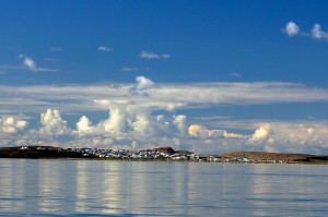 The view of Kugluktuk from the boat, nestled on the north side of the hills surrounding the town. (Photo credit: Robie Macdonald)